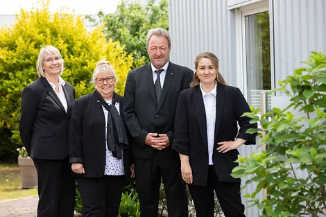 Vier Mitarbeitende des Beerdigungsinstituts Artur Ode stehen vor dem Firmengebäude in Bad Schwartau
